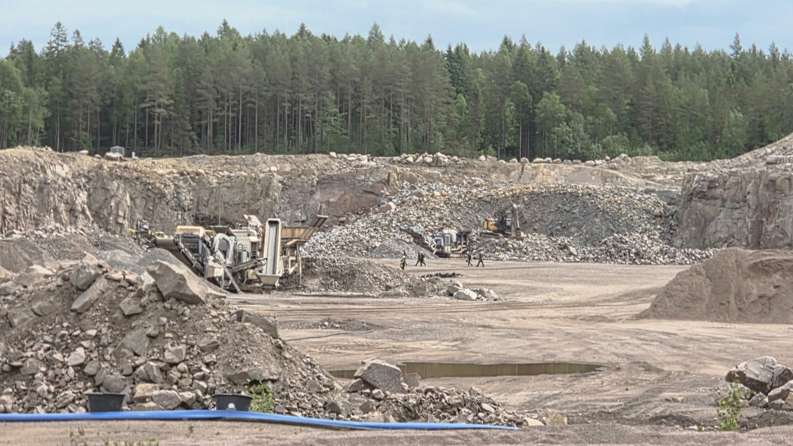 Krossutrustning, bergvägg och materialhögar i Brodderuds bergtäkt