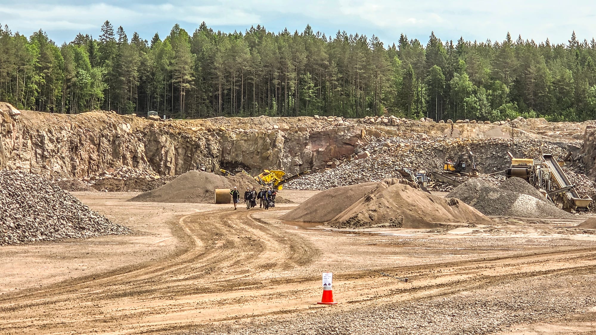Bergvägg, materialhögar och krossutrustning i Brodderuds bergtäkt