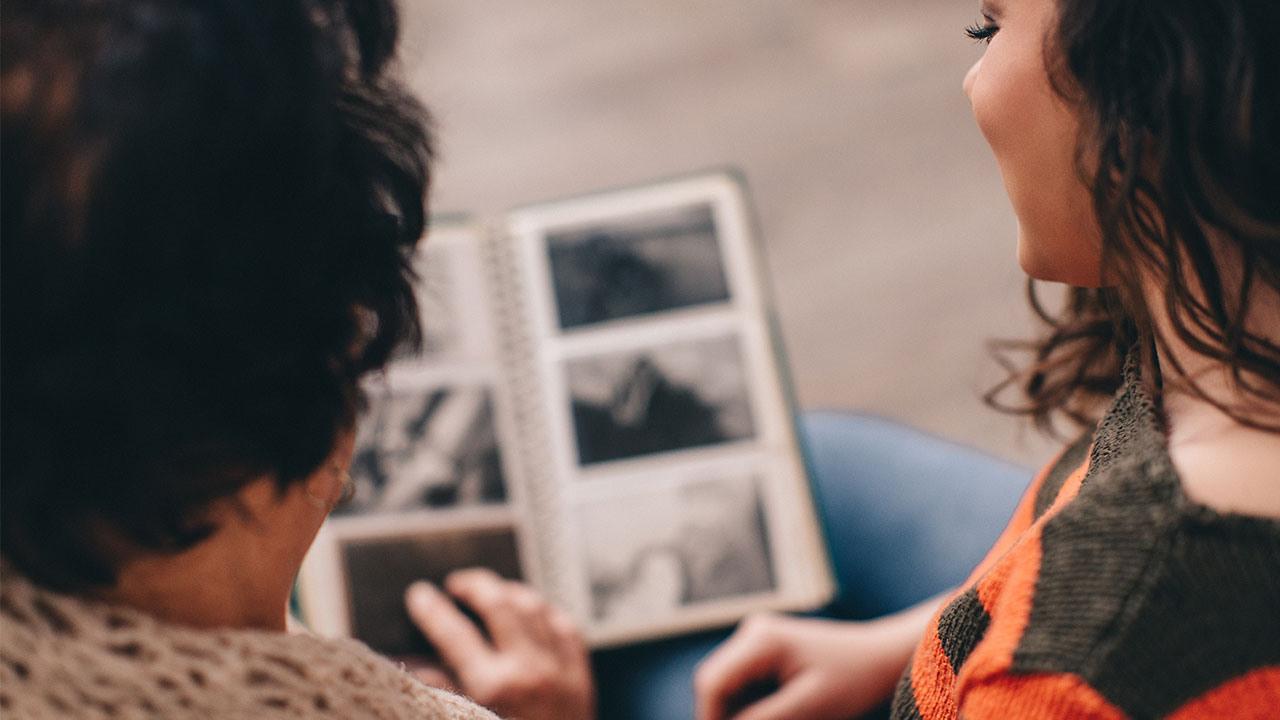 Två personer tittar i ett fotoalbum – bild från Fonus webbplats